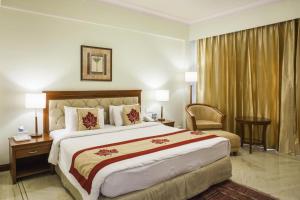 a hotel room with a large bed and a chair at Clarion Bella Casa at Airport in Jaipur