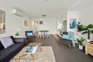 sala de estar con sofá, sillas y mesa en Beach Apartment Port Melbourne, en Melbourne