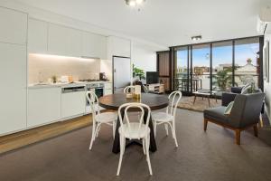 Beach Apartment Port Melbourne في ملبورن: مطبخ وغرفة طعام مع طاولة وكراسي
