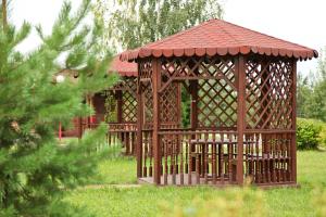 a wooden gazebo in the grass with a tree at AZIMUT Hotel Kostroma in Kostroma