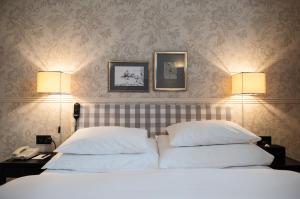 a bedroom with a bed with two pillows and two lamps at Hotel Kindli in Zurich