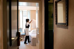 a woman standing in a room looking out the window at Hotel Kindli in Zurich