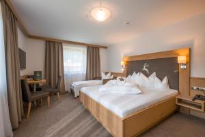 a hotel room with two beds and a desk at Hotel Gasthof Jäger Zillertal in Schlitters