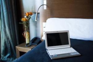 einen Laptop auf einem Bett in einem Hotelzimmer in der Unterkunft TaCH Madrid Airport in Madrid