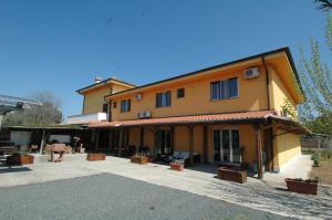 ein großes gelbes Gebäude mit einer Terrasse davor in der Unterkunft Albergo Luisss in Marina di Grosseto