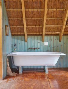 uma banheira branca num quarto com tecto em madeira em Driftwood Treehouse em Sunrise-on-Sea