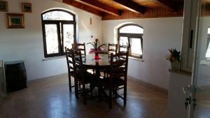 a dining room with a table and chairs and two windows at Apartmani Jašarević in Martinšćica
