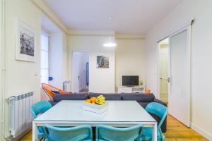 a living room with a white table and blue chairs at Apartamento Urumea in San Sebastián