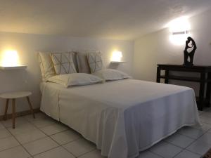 a bedroom with a large bed with white sheets and pillows at Maison d'hôtes Antoinette in Cogolin
