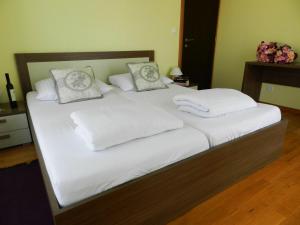 1 cama grande con sábanas y almohadas blancas en Smaragdna Villa YourCroatiaHoliday, en Premantura