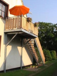 einen Balkon mit orangefarbenem Regenschirm auf einem Gebäude in der Unterkunft Ferienwohnung Greschke in Prerow