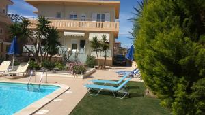 a villa with a swimming pool and two lounge chairs at Nicolas Studios & Apartments in Agia Marina Nea Kydonias