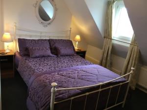 ein Schlafzimmer mit einem Bett mit einer lila Bettdecke und einem Fenster in der Unterkunft Morlea in Llandudno
