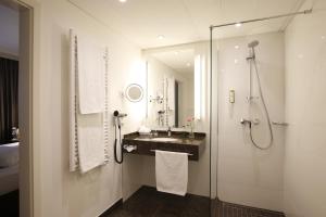 a bathroom with a shower and a sink and a mirror at Parkhotel Wittekindshof in Dortmund