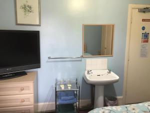 a small bathroom with a sink and a mirror at St. James's Guest House in London