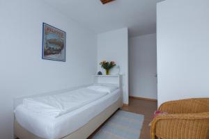 een slaapkamer met een wit bed en een stoel bij Hotel Alpha in Luzern