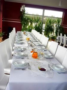 a long table with white plates and glasses on it at Czarna Perła in Ostrowo