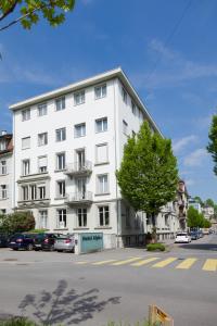 un bâtiment blanc avec un arbre devant lui dans l'établissement Hotel Alpha, à Lucerne