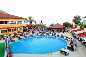 un grupo de personas sentadas alrededor de una gran piscina en Club Dizalya, en Konaklı