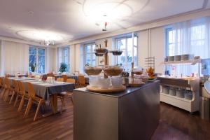 a restaurant with a long table with tables and chairs at Hotel Alpha in Lucerne
