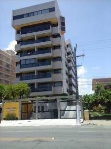 ein hohes Gebäude mit einem Zaun davor in der Unterkunft Beira Mar da Pajuçara in Maceió