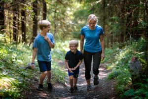 a woman and two boys walking on a trail in the woods at Fagernes Camping in Fagernes