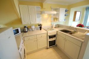 a small kitchen with white cabinets and a sink at Sea View 3 Promenade in Sheringham