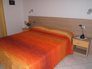 ブレンゾーネにあるAppartamenti Maryのベッドルーム1室(オレンジ色のベッド1台、ランプ付きのナイトスタンド付)