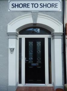a black door with a sign that reads store to store at Shore to Shore in Llandudno