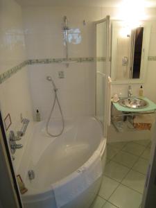 La salle de bains blanche est pourvue d'une baignoire et d'un lavabo. dans l'établissement Hôtel Le Manoir aux Vaches, à Yvetot