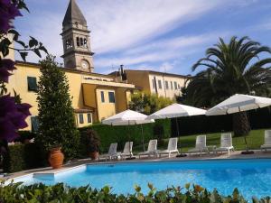 basen z parasolami i budynek z wieżą zegarową w obiekcie Albergo Roma w mieście Casciana Terme