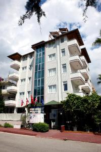 een hoog wit gebouw met vlaggen ervoor bij Sempati Apart Hotel in Alanya
