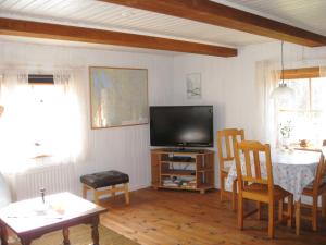 a living room with a television and a table and chairs at Tildas Urshult in Urshult