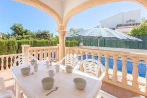 a white table and chairs on a balcony with a pool at Monte Verde in Jávea