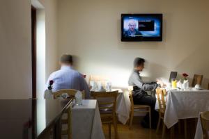 2 hommes assis dans un restaurant avec une télévision murale dans l'établissement The Brent Hotel - London - Wembley, à Londres