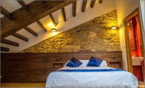 ein Schlafzimmer mit einem Bett mit einer Steinmauer in der Unterkunft Oxford Suites Santiago de Compostela in Santiago de Compostela