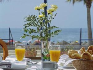 une table avec deux verres de jus d'orange et un vase de fleurs dans l'établissement Hotel Marlin Antilla Playa, à La Antilla
