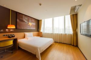 Habitación de hotel con cama, escritorio y TV. en IU Hotel Wujiang Huadong Business City Tongli en Suzhou