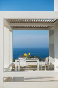 un patio con mesa, sillas y el océano en Sofia Luxury Villas, en Panormos Rethymno