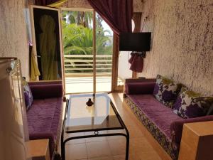 a living room with purple couches and a glass table at Residence Tafat in Agadir