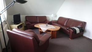 sala de estar con sofás de cuero y mesa en Ferienwohnung Heike Heitmann, en Eystrup
