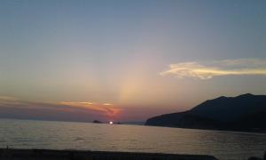 a sunset over the water with a mountain in the background at Buljarica Bay Apartments in Petrovac na Moru