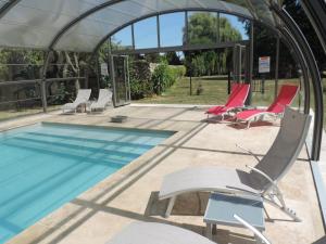 a swimming pool with lounge chairs and a swimming pool at Cèdre et Charme in Saint-Branchs