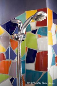 a bathroom sink with a shower head on a mosaic tile wall at Hotel Intervallo in Torre Lapillo