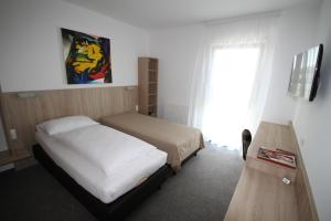 a bedroom with two beds and a television and a window at Bernstein-Motel Marchegg in Marchegg