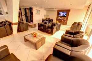 a living room with leather chairs and a table at Hotel Vela Azul in Balneário Camboriú