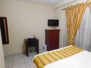 a bedroom with a bed and a desk and a television at Hotel San Jose Hostal in San Salvador