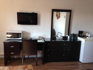 a room with a desk with a microwave and a mirror at Motel le Phare in Plessisville