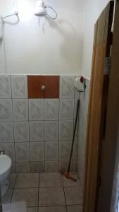 a bathroom with a toilet and a tiled wall at Pousada Sempre Viva in Milho Verde