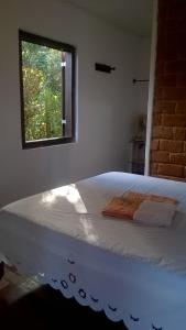 uma cama branca num quarto com uma janela em Pousada Sempre Viva em Milho Verde